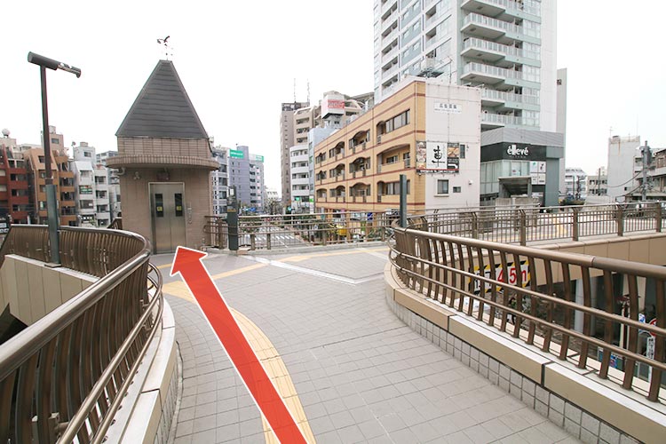 歩道橋を直進し、Y字路で左側階段または正面のエレベーターより下の歩道へ下ります。